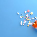 spilled prescription pills from a bottle on a blue background